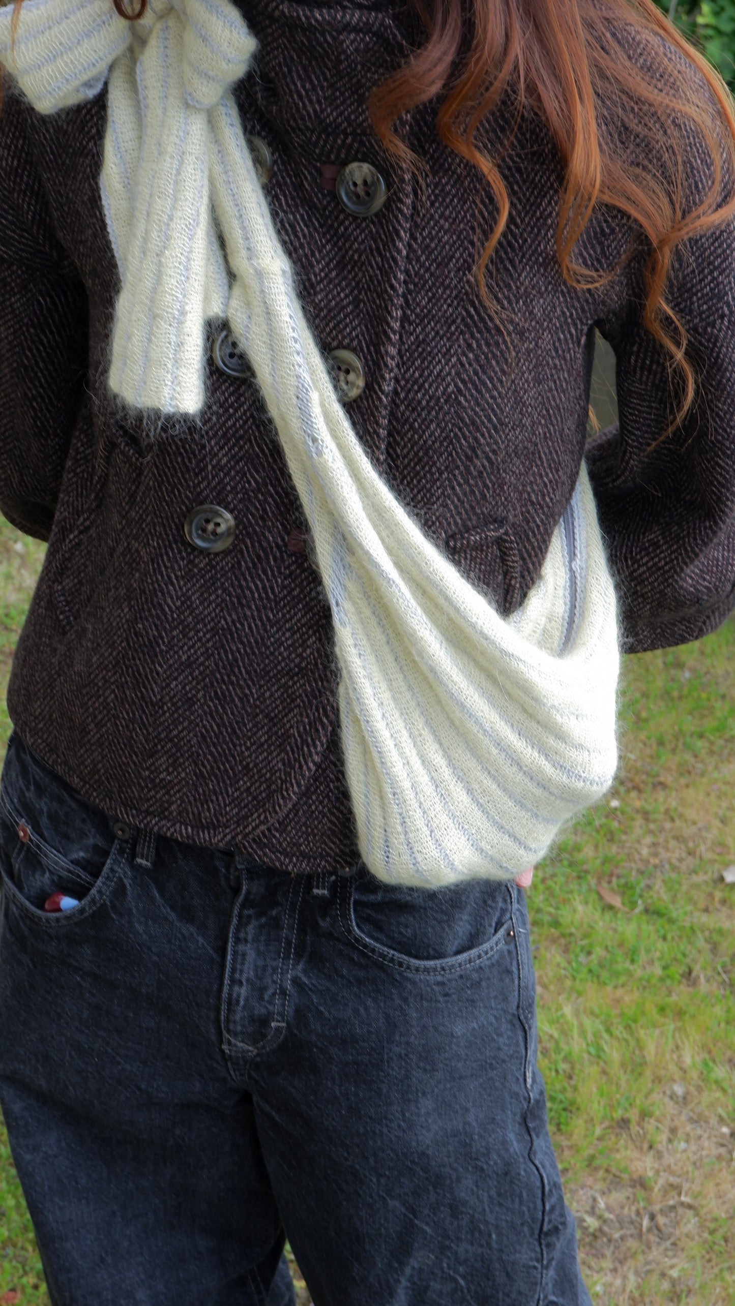 Person wearing a dark coat carrying a yellow bag outdoors.