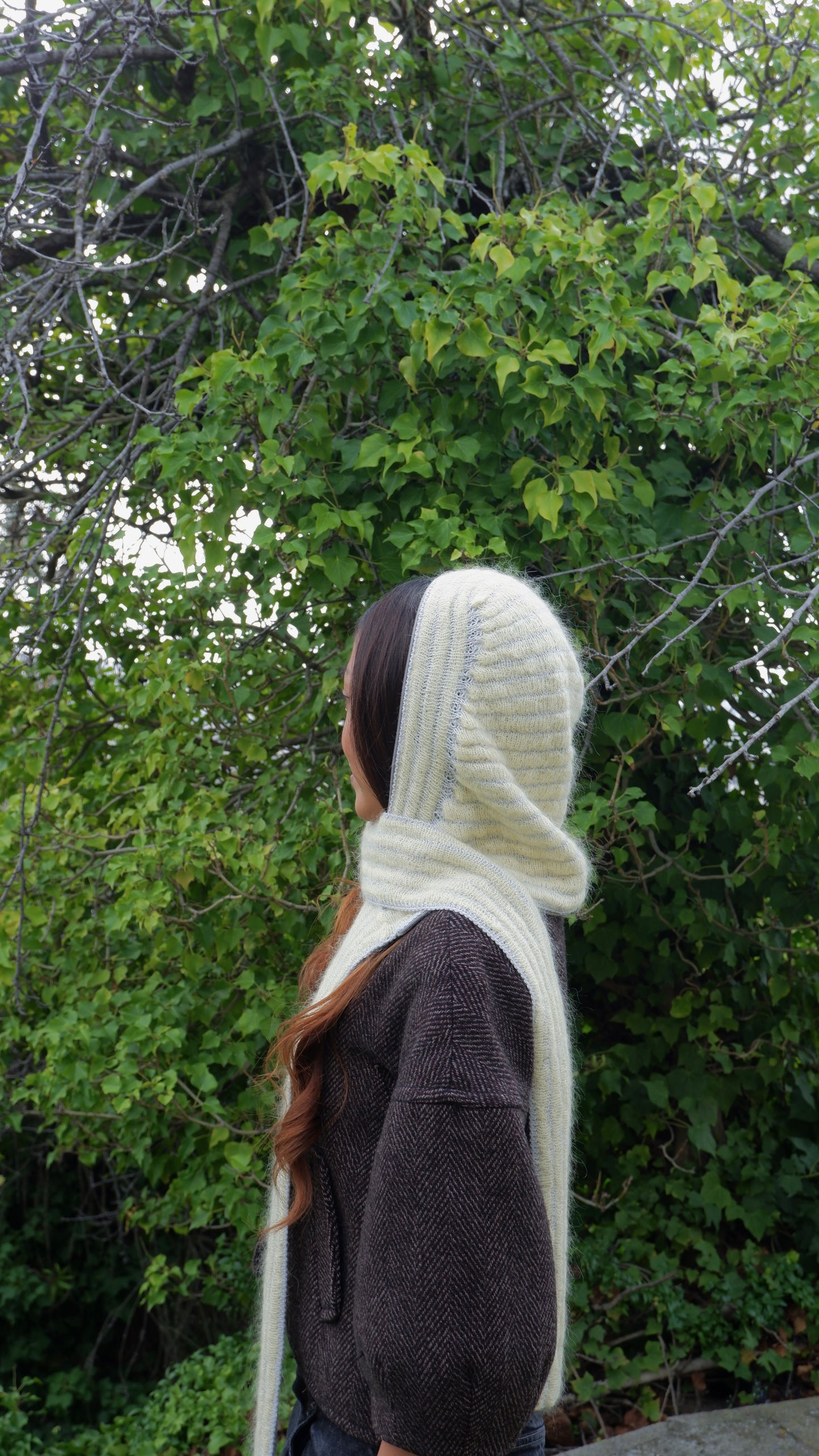 Person wearing a yellow hooded garment against a green leafy background